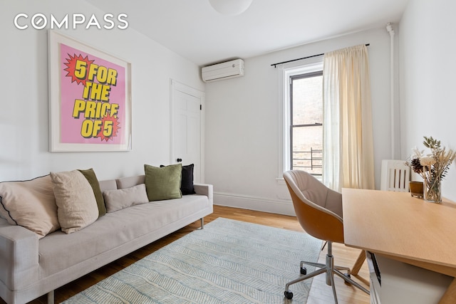 office area with an AC wall unit, light wood-style flooring, and baseboards