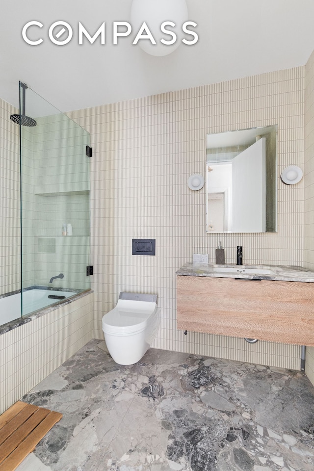 bathroom with vanity, tile walls, toilet, and tiled shower / bath