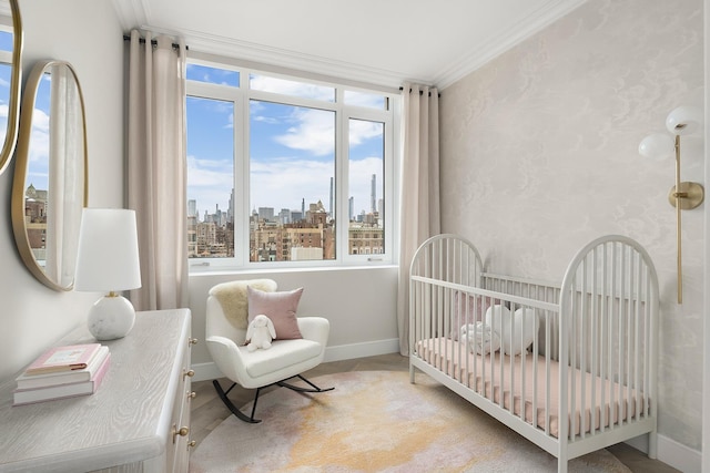 bedroom featuring a nursery area, ornamental molding, baseboards, and a city view