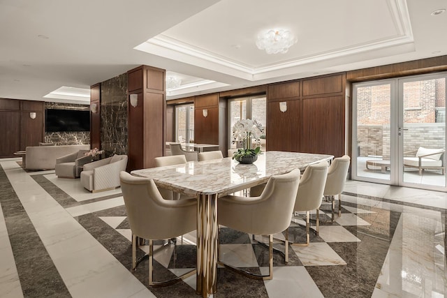 interior space with marble finish floor, wooden walls, ornamental molding, and a raised ceiling