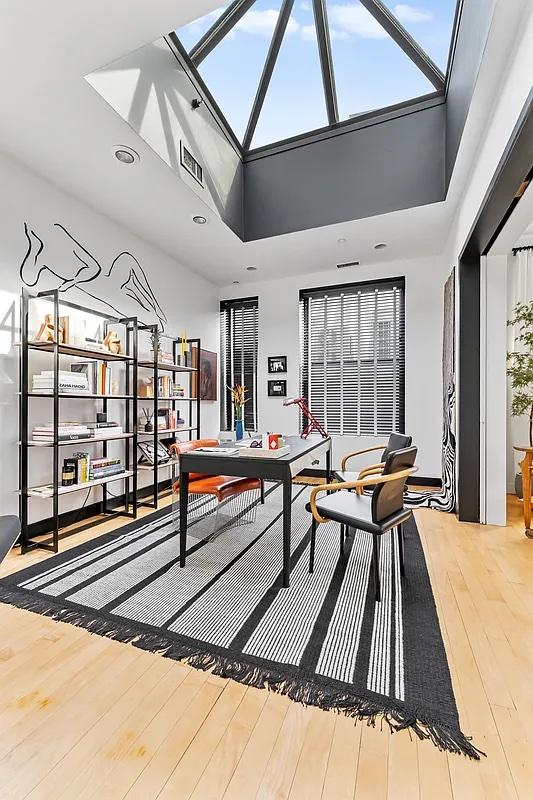 recreation room featuring a skylight, a high ceiling, and hardwood / wood-style floors