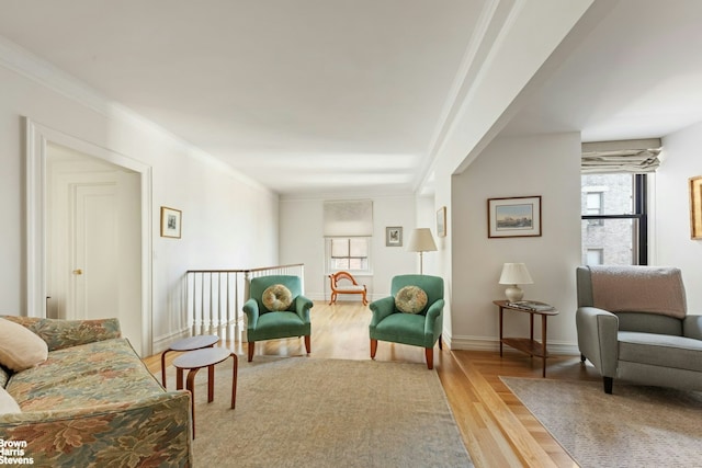 living area featuring ornamental molding, light wood-style flooring, and baseboards