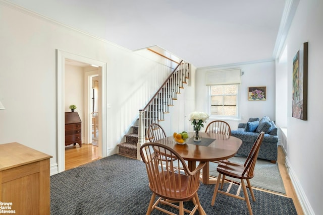 dining space with ornamental molding, carpet, baseboards, and stairs