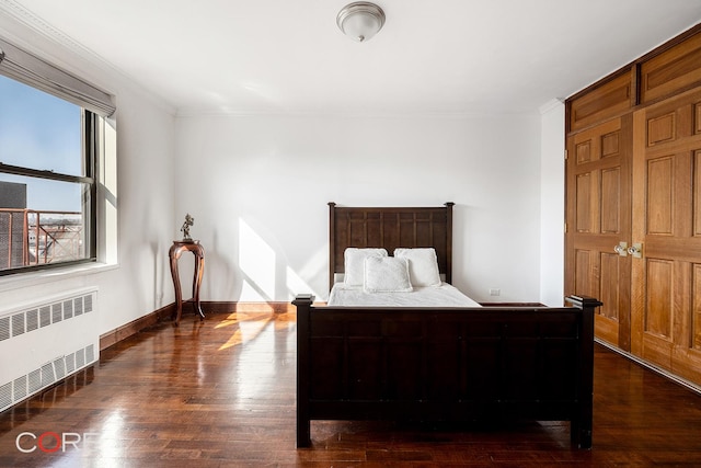 bedroom featuring dark wood-style floors, radiator, ornamental molding, and baseboards