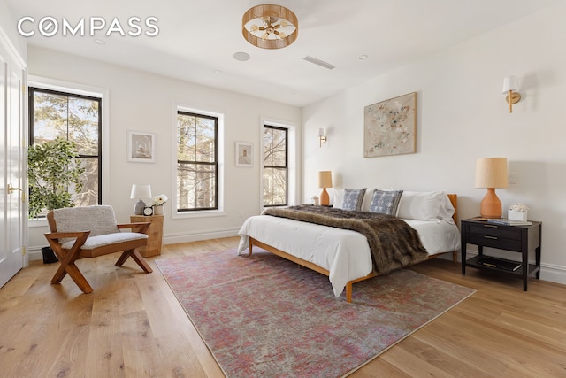 bedroom with light wood-style flooring, visible vents, and baseboards