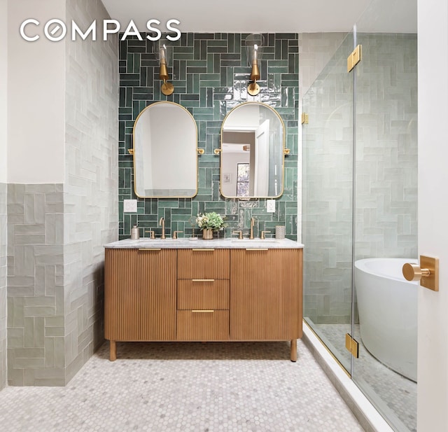 full bath featuring tile patterned floors, a soaking tub, tile walls, and double vanity