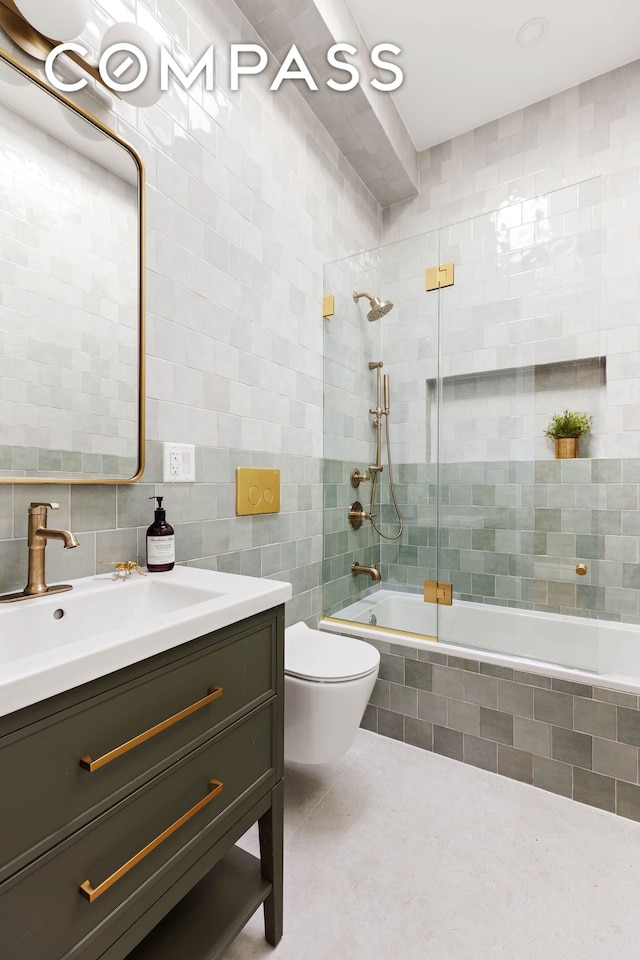 full bathroom featuring toilet, tile patterned floors, tiled shower / bath combo, vanity, and tile walls