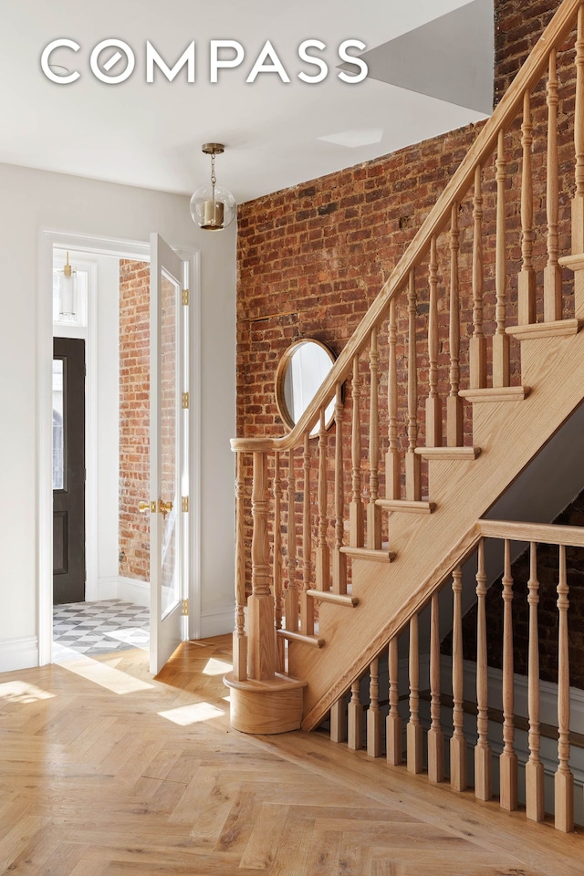 staircase with baseboards and brick wall