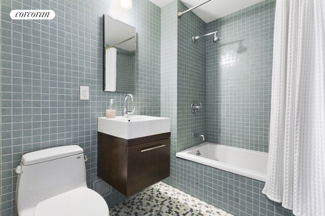 bathroom with tiled shower / bath, toilet, tile walls, and vanity