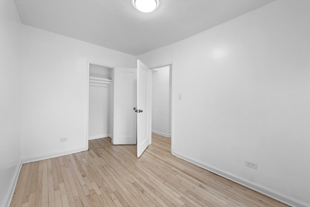 unfurnished bedroom with a closet, baseboards, and light wood finished floors