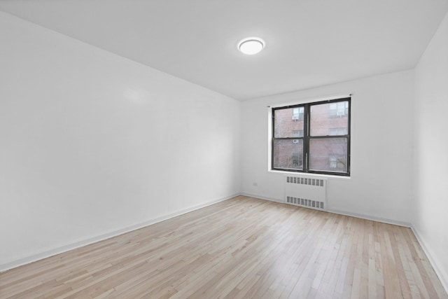 spare room with light wood-style floors and radiator heating unit