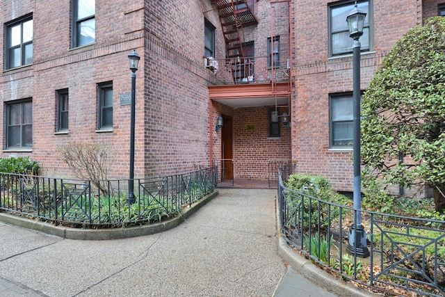 entrance to property featuring brick siding and fence