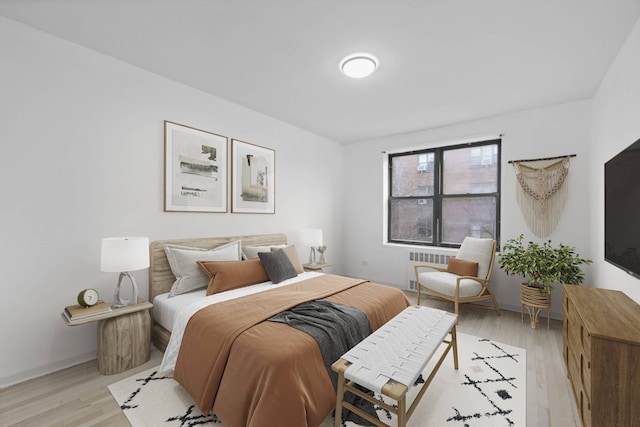 bedroom featuring baseboards, light wood-type flooring, and radiator