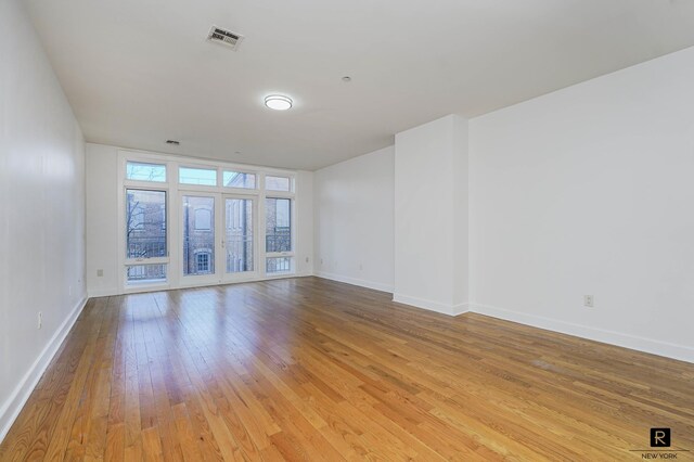 empty room featuring baseboards, visible vents, and light wood finished floors