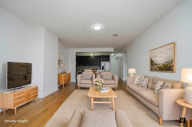 living room with baseboards, visible vents, and light wood-type flooring