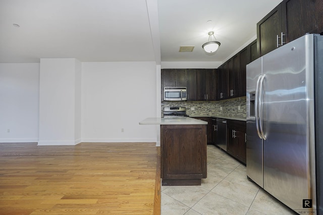 kitchen with light countertops, baseboards, backsplash, and stainless steel appliances