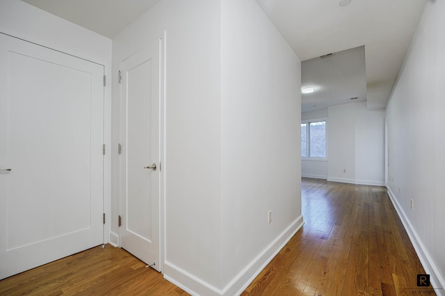 hallway with baseboards and hardwood / wood-style floors