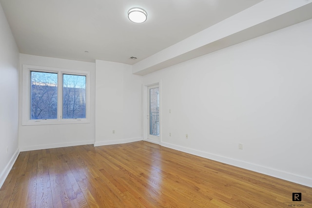 spare room with baseboards, visible vents, and wood finished floors