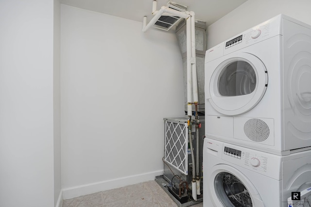 washroom with baseboards, laundry area, and stacked washer and dryer