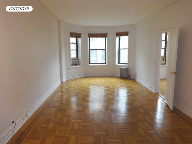 spare room with radiator heating unit, cooling unit, visible vents, and baseboards