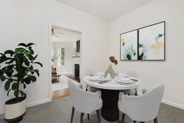 dining space with a fireplace with raised hearth, carpet, and baseboards