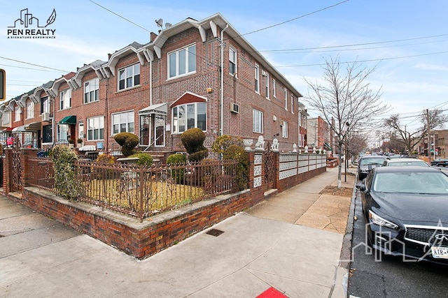 view of side of property featuring a fenced front yard, a residential view, and brick siding