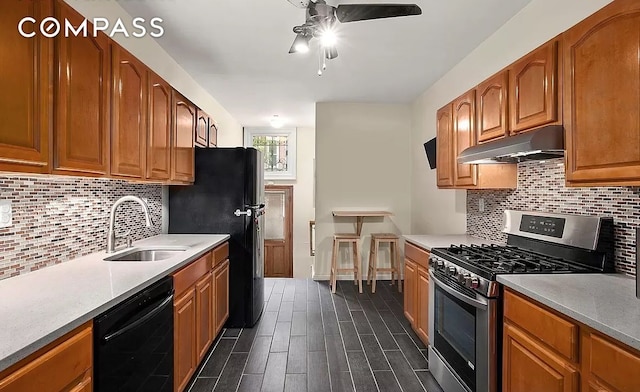 kitchen featuring backsplash, dark wood-type flooring, under cabinet range hood, black appliances, and a sink