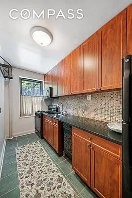 kitchen featuring dark countertops, brown cabinets, backsplash, and black appliances