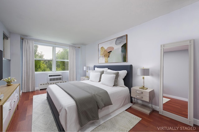 bedroom with a baseboard heating unit, baseboards, dark wood-style flooring, and a wall mounted air conditioner