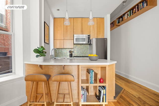 kitchen with modern cabinets, a peninsula, stainless steel appliances, light countertops, and a sink