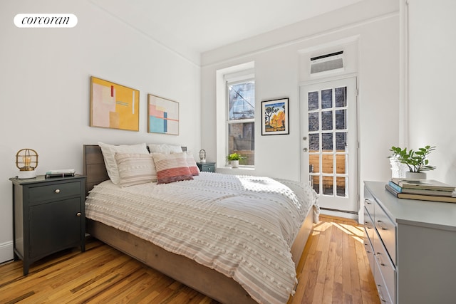 bedroom with access to outside, visible vents, and light wood finished floors