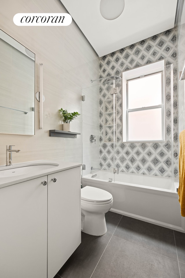 full bathroom featuring toilet, tile patterned flooring, vanity, shower / washtub combination, and tile walls