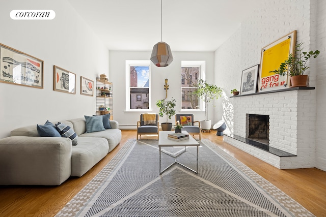 living room featuring visible vents, a fireplace, baseboard heating, and wood finished floors