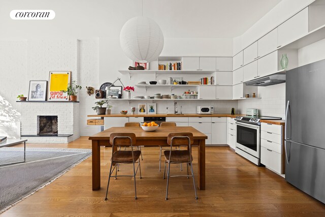 kitchen featuring stainless steel appliances, visible vents, a sink, wood finished floors, and under cabinet range hood