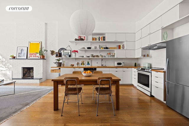 kitchen featuring visible vents, under cabinet range hood, wood finished floors, stainless steel appliances, and a sink