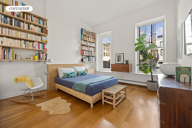 bedroom with wood-type flooring and a baseboard radiator