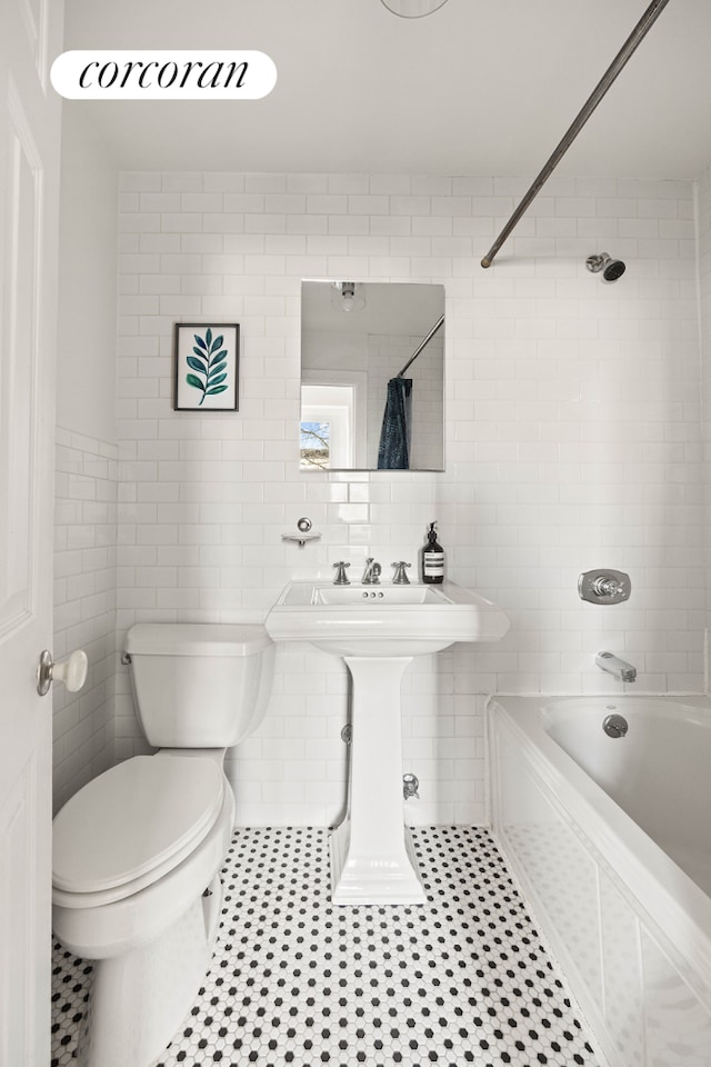 bathroom featuring tile patterned flooring, shower / bathtub combination with curtain, tile walls, and toilet