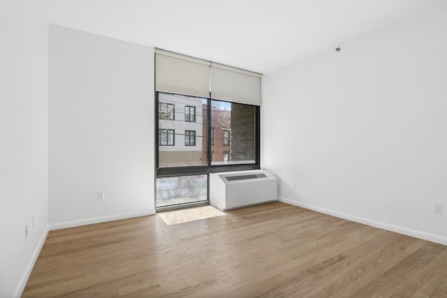 spare room featuring light wood-style floors, radiator, and baseboards