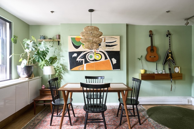 dining space with a baseboard radiator, wood finished floors, and baseboards