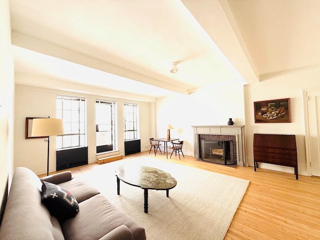 living room with beam ceiling, a fireplace, and wood finished floors