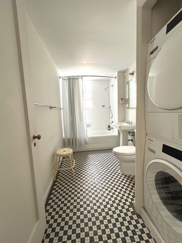 full bathroom featuring toilet, shower / bath combo with shower curtain, stacked washer / drying machine, and tile patterned floors