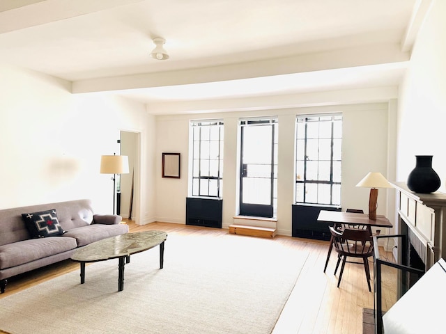 living area with light wood-type flooring, beamed ceiling, and a fireplace