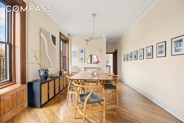 dining area with ornamental molding, light wood-style flooring, and baseboards