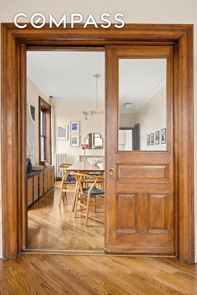 corridor featuring radiator, light wood-style floors, and ornamental molding