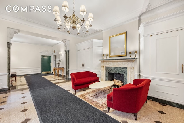 living area with a decorative wall, granite floors, a premium fireplace, crown molding, and wainscoting