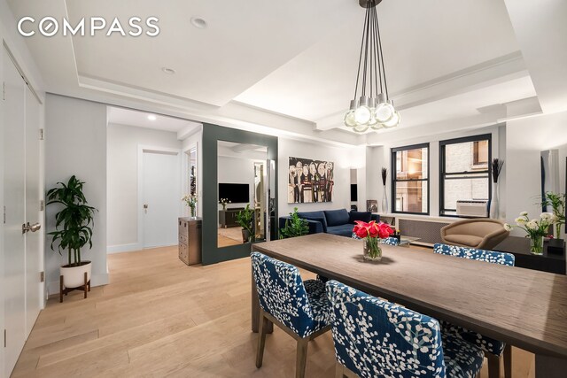 dining area featuring a tray ceiling, radiator, and light wood finished floors