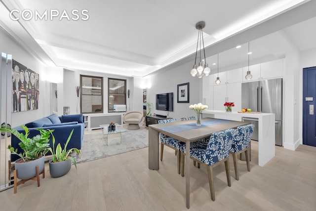 dining space featuring a raised ceiling, radiator, and light wood finished floors