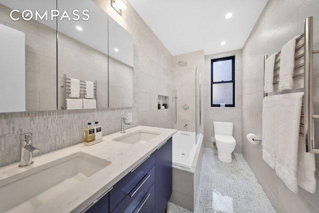 full bath featuring a sink, toilet, shower / washtub combination, and tile walls