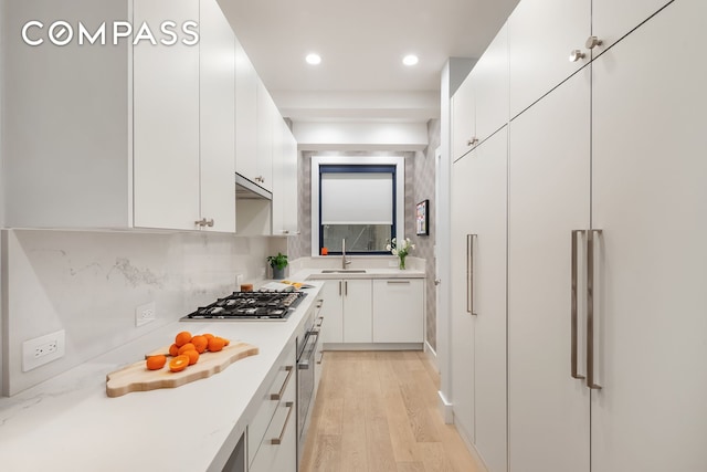 kitchen with appliances with stainless steel finishes, a sink, white cabinets, recessed lighting, and backsplash