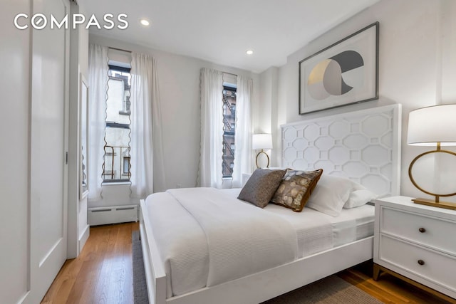 bedroom with baseboard heating, wood finished floors, and recessed lighting